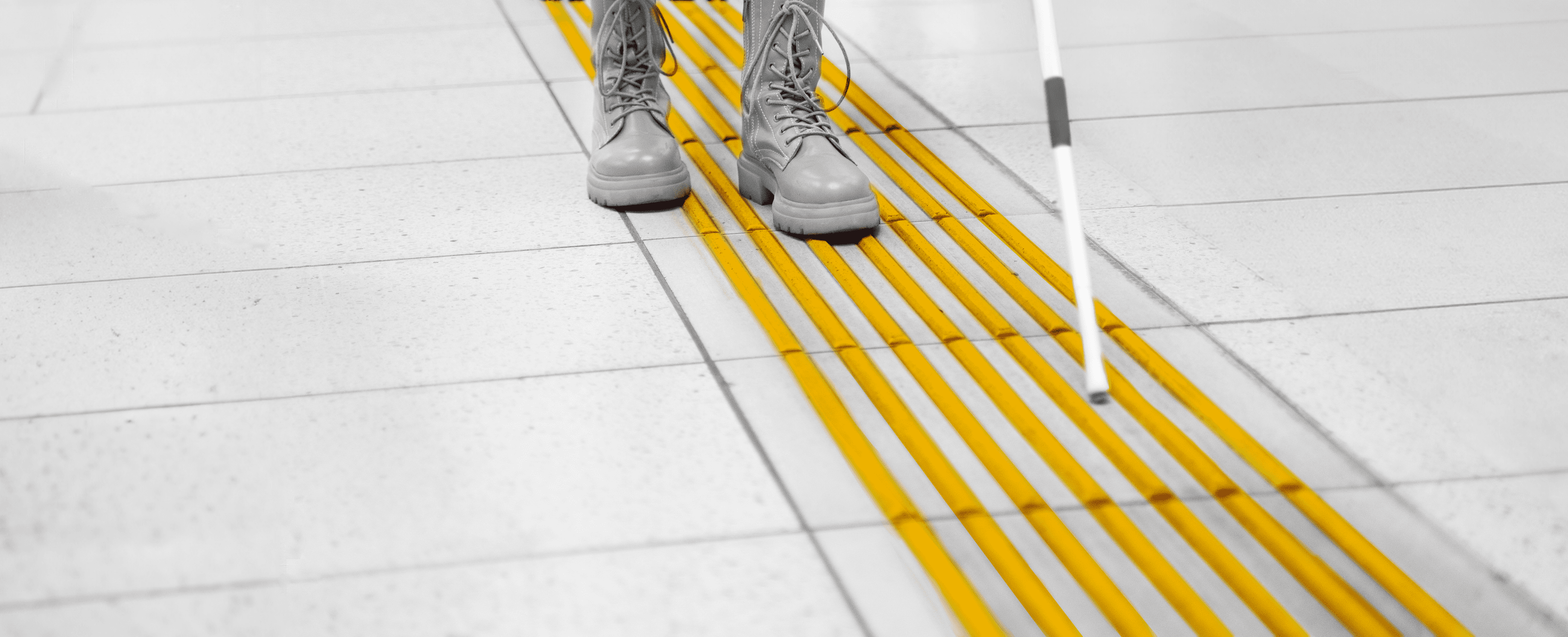 Directional tactile paving in the signature Gyde yellow with a user using a white cane.